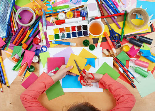 Children cutting colourful paper at the kids craft table